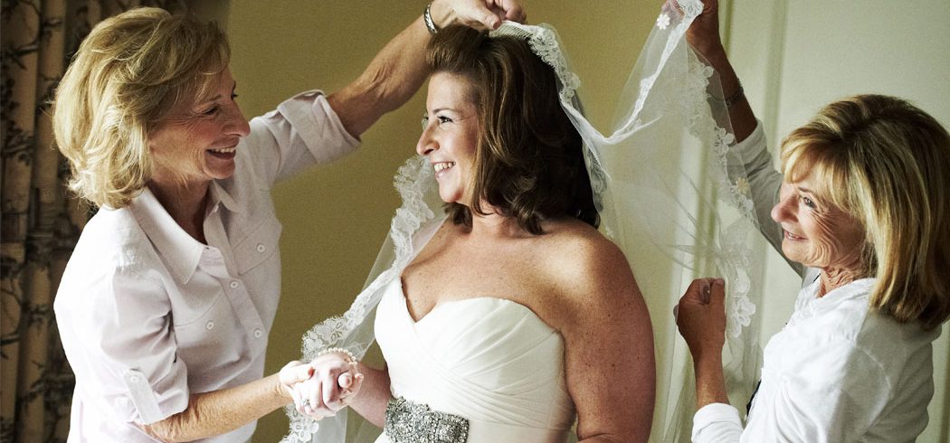 Bride smiling and putting veil on while getting ready for wedding day in Philadelphia, PA - Event Planner