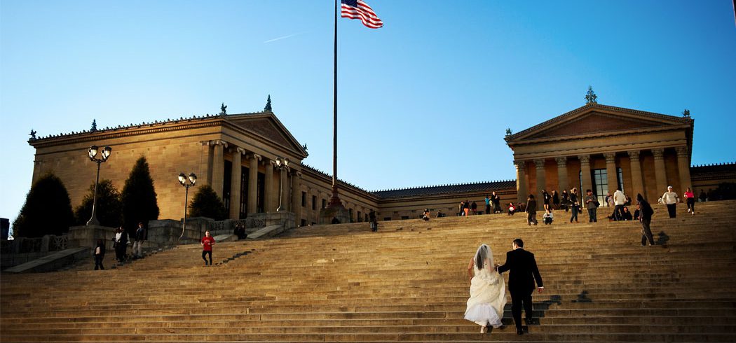 Bride and Groom walk up the Philadelphia Art Museum steps during outside wedding portraits in Philadelphia, PA - Event Planner