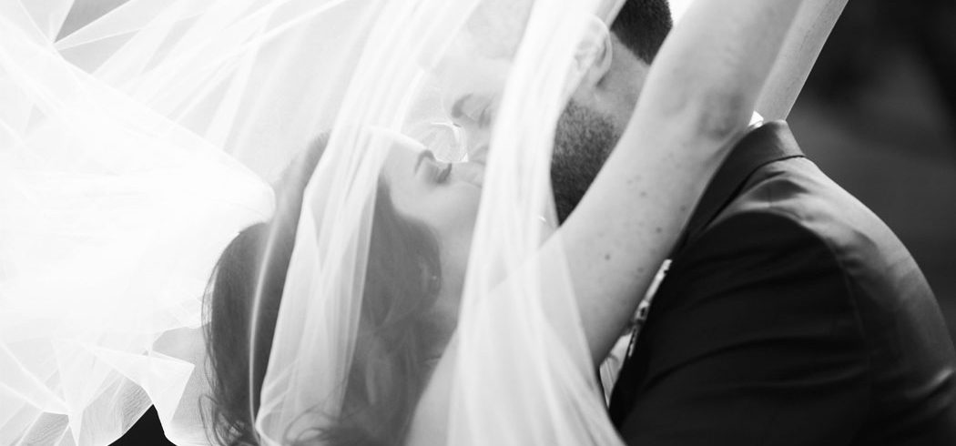 Bride and Groom kiss and veil is flowing during outside wedding portraits in Philadelphia, PA - Event Planner