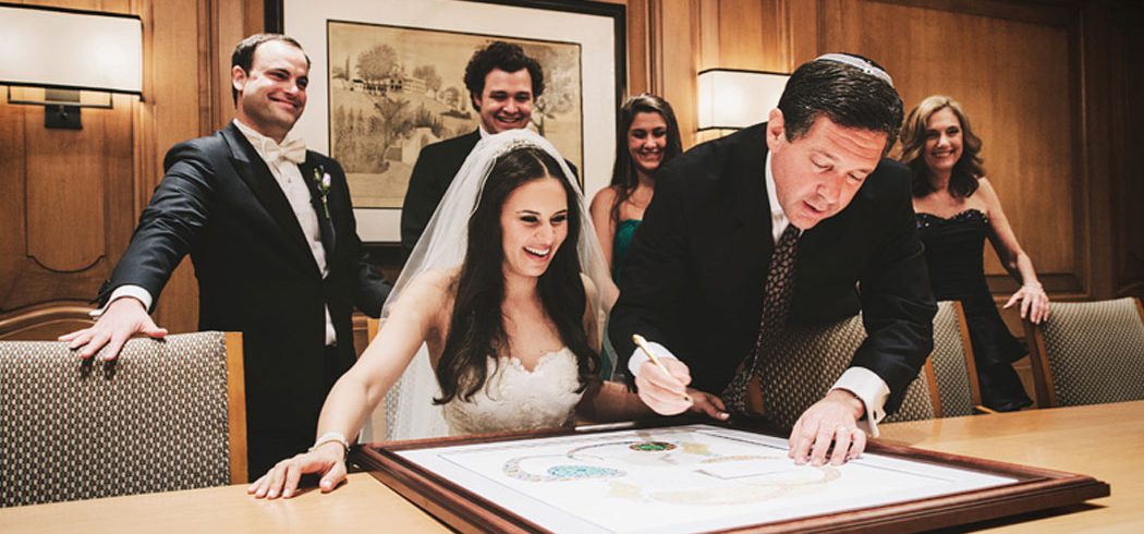 Bride and Groom sign document surrounded by friends in Philadelphia, PA - Event Planner