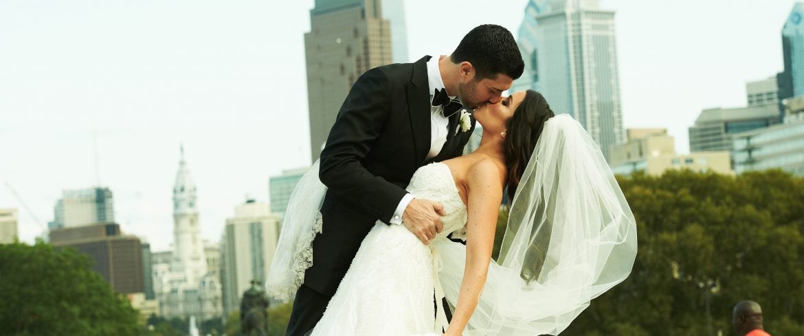 Groom dips Bride and kissed during outside wedding portraits in Philadelphia, PA - Event Planner